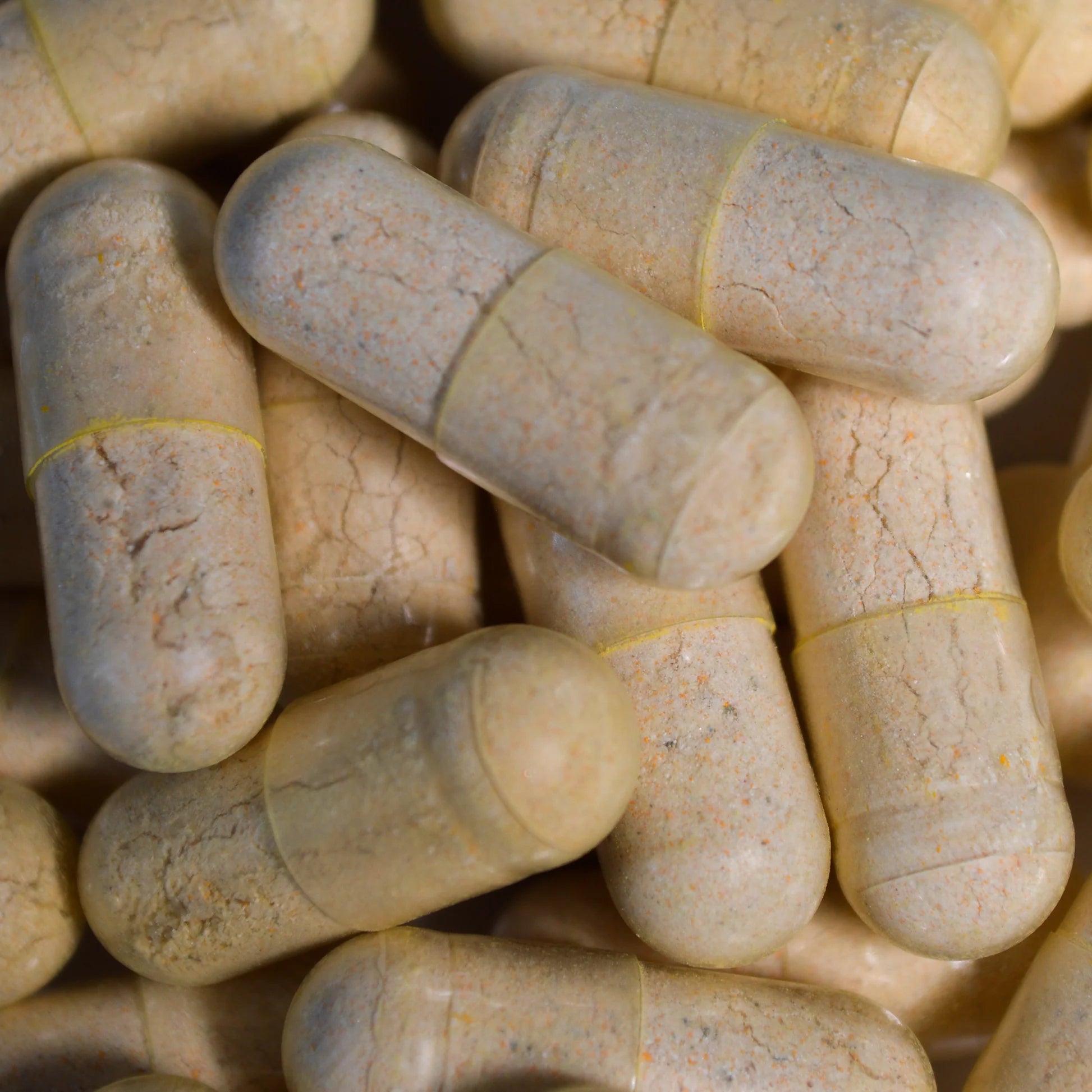Close-up of beige capsules with yellow lines on a matching background